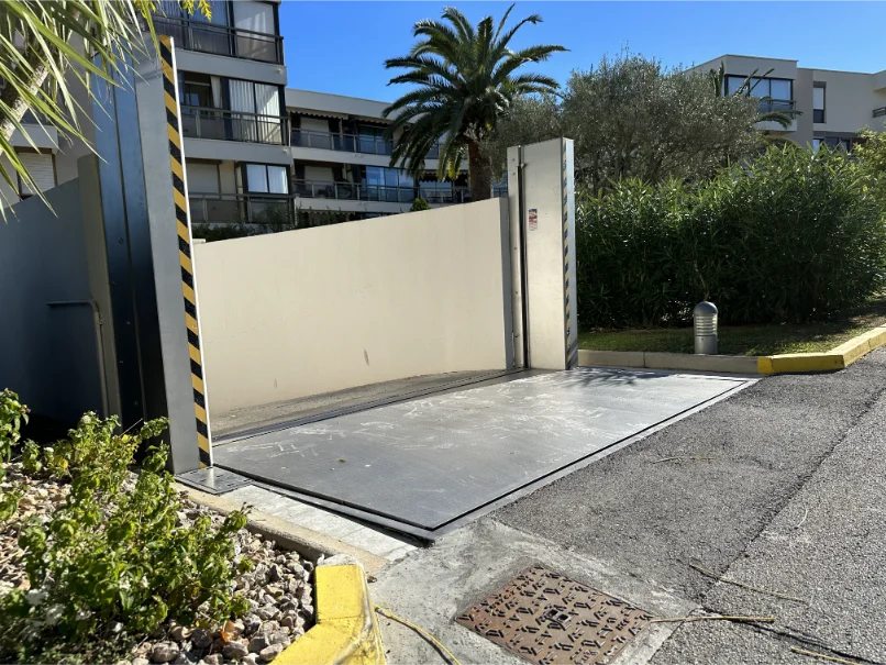 Selbstaktivierendes Edelstahl-Klappschott an Einfahrt zu Wohnanlage – Hochwasserbarriere schützt Tiefgarage vor Starkregen und Überschwemmungen.