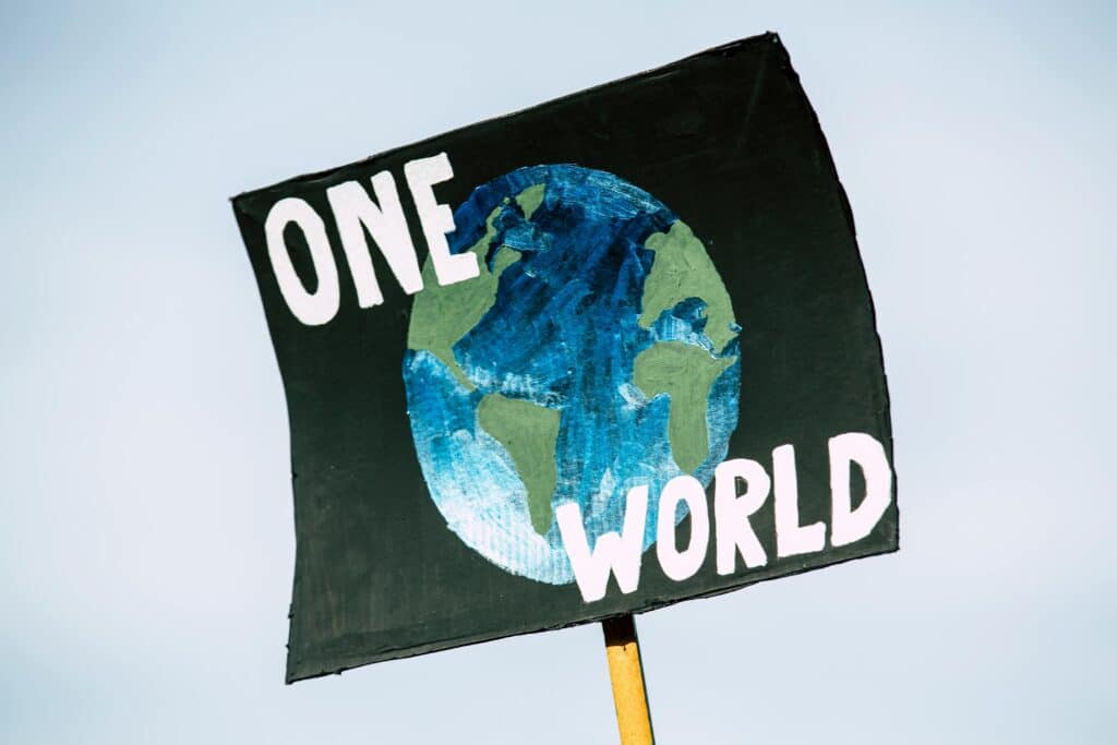Nahaufnahme eines Protestschildes mit der Abbildung der Erde und der Aufschrift „One World“, das das Bewusstsein für den Klimawandel symbolisiert.