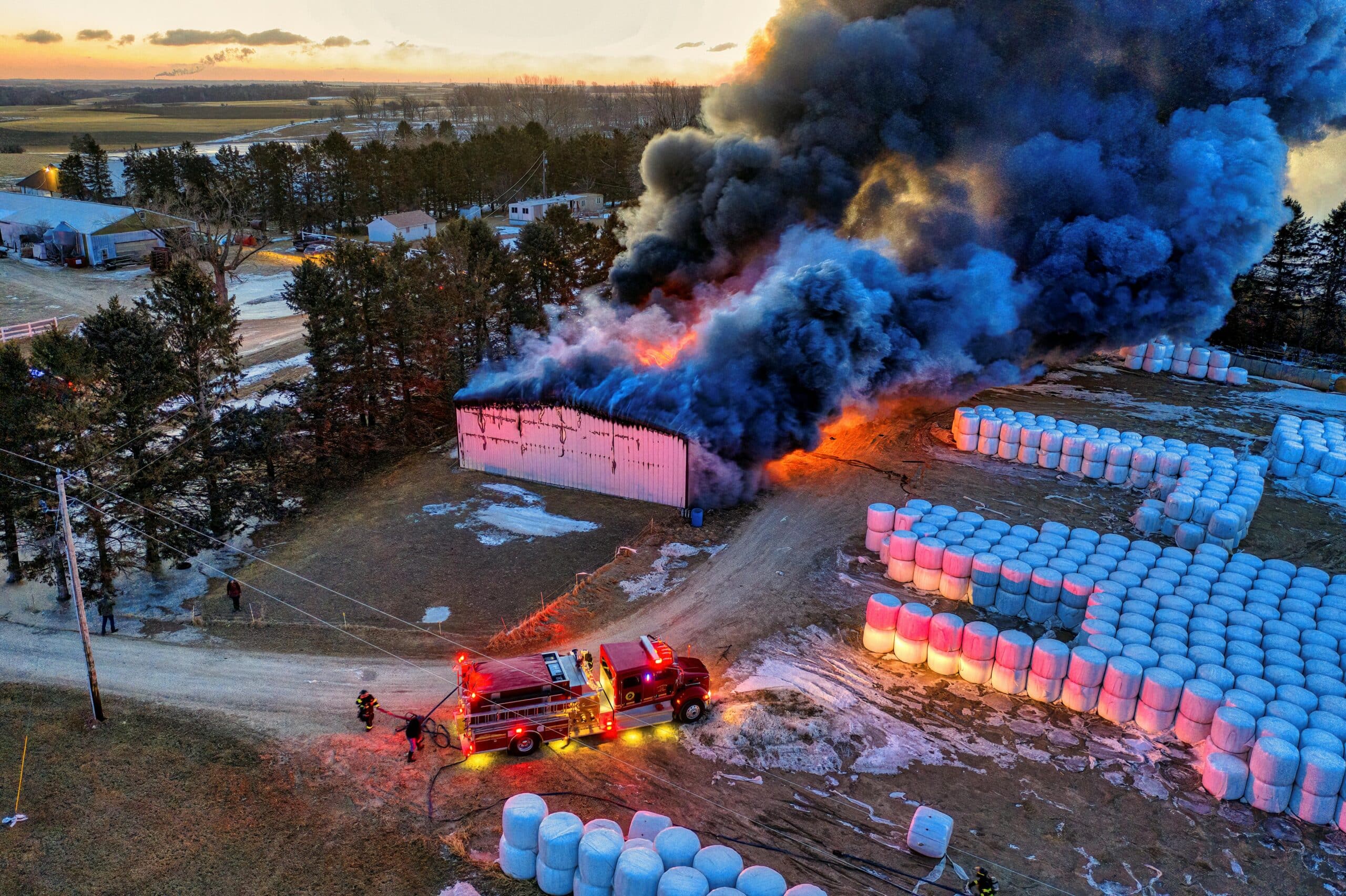 Feuerwehrleute bekämpfen einen heftigen Brand, der ein Gebäude auf dem Land erfasst hat – aufgenommen aus der Vogelperspektive.